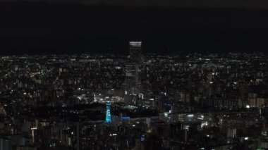 Geceleri Metropolis 'in havadan panoramik görüntüsü. Uzun, modern bir gökdelen. Çevredeki kasaba inşaatının üstünde. Osaka, Japonya.