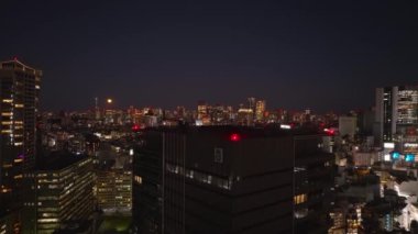 Şehirdeki çok katlı binanın havadan yükselen görüntüleri. Metropolis 'in gece manzarası ortaya çıkıyor. Tokyo, Japonya.