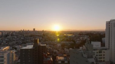 Güneşin batmasına karşı yerleşim yerlerindeki binaların havadan yükselen görüntüsü. Tokyo, Japonya.
