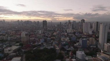 Gökyüzünün rengarenk gündoğumuna karşı yüksek binaları olan büyük şehrin panoramik görüntüsü. Manila, Filipinler.