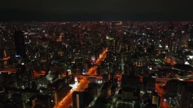 Geceleri büyük şehrin havadan panoramik görüntüsü. Metropolis 'te aydınlatılmış caddeler ve binalar. Osaka, Japonya.
