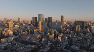 Gökyüzü panoramik manzaralı modern şehir merkezi yüksek katlı ofisleri ya da konut kuleleri olan. Sahne batan güneşle aydınlatıldı. Tokyo, Japonya.