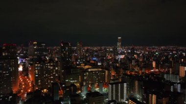 Akşamları metropoldeki konutların üzerinden uçuyor. Şehir merkezindeki çok katlı apartmanlar. Osaka, Japonya.