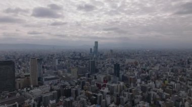 İleri, büyük şehrin üzerinde uçar. Bulutlu gökyüzünün altındaki Metropolis 'in hava panoramik görüntüleri. Kasaba gelişiminin yoğunluğu yüksek. Osaka, Japonya.