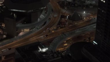 Şehirdeki çok katlı yol kavşağından geçen arabaların yüksek açılı görüntüsü. Gece ulaşım altyapısı. Osaka, Japonya.