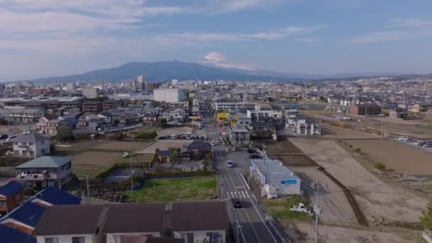 在城市住宅区的街道上方飞行 郊区低矮的建筑物和雪峰覆盖的富士山相距很远 — 图库视频影像