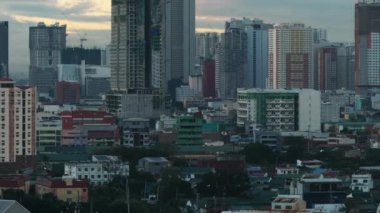 Şehir merkezindeki evlerin yüksek açılı manzarası. Eğim gökyüzündeki renkli bulutlara karşı yüksek binaları ortaya çıkarıyor. Manila, Filipinler.