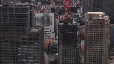 Şehirdeki modern yüksek binaların etrafında uçmak. Eğim, renkli gündoğumuna karşı şehir manzarasını ortaya çıkarır. Osaka, Japonya.