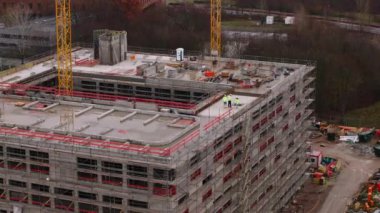 İnşaat alanında teftiş yapan mühendislerin hava kaydırak ve pan görüntüsü. Çok katlı ticari bir obje inşa ediliyor. Frankfurt am Main, Almanya.