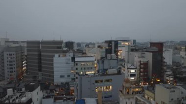 Şehir merkezindeki modern çok katlı binaların hava kaydırak ve pan görüntüleri. Alacakaranlıkta aydınlanmış caddeyi açığa çıkarmak. Kyoto, Japonya.