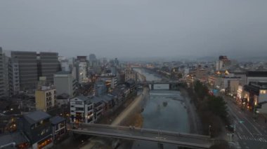 Yağmurlu bir akşamda Kamo nehri ve köprülerin üzerinden uç. Gün batımında şehirde melankolik bir hava var. Kyoto, Japonya.