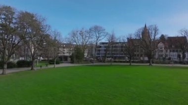 Baharda parktaki çimlerin ve ağaçların havadan yükselen görüntüleri. Kule ve panoramik şehir manzarası ile kiliseyi gözler önüne sermek. Basel, İsviçre.