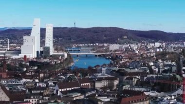 Nehir ve köprülü şehir manzarası. Tarihsel şehir merkezi, modern yüksek binalı Roche Kulesi gökdelenleriyle çelişiyor. Basel, İsviçre.