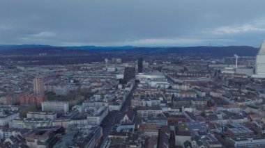 Şehir merkezindeki binaların üzerinden hava kararınca ilerliyorlar. Sergi Merkezine gidiyorum. Basel, İsviçre.