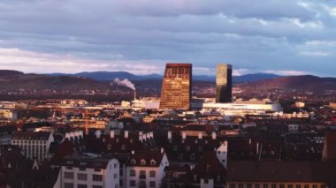 Şehrin altın saatinde iki yüksek binasının hava kaydırağı ve pan görüntüleri. Tarihi evleri ve kule vincini gözler önüne seriyor. Basel, İsviçre.