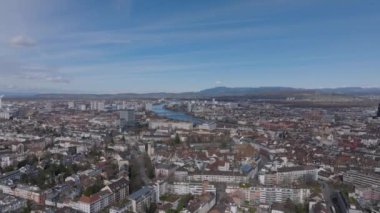 Şehirdeki binaların üzerinden ileriye doğru uçuyor. Nehir ve köprülü panoramik şehir manzarası. Basel, İsviçre.