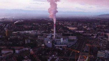 Tüten bacası olan endüstriyel banliyölerin havadan görünüşü. Alacakaranlık vakti şehrin kenar mahallelerinin panoramik manzarası. Basel, İsviçre.