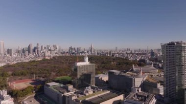 NHK Yayın Merkezi kompleksinin üzerinde uçuyor. Yoyogi Parkı ve Metropolis ufuk çizgisinin havadan panoramik görüntüsü. Tokyo, Japonya.