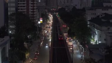 Şehir merkezinde akşam vakti banliyö trenini takip ediyor. Yoğun yol ve şehirdeki yüksek binalar. Manila, Filipinler.