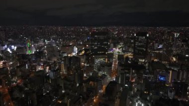 Geceleri Metropolis 'in havadan panoramik görüntüsü. Popüler gece hayatı bölgesinde aydınlatılmış binalar. Osaka, Japonya.