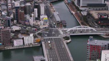 Şehirdeki trafiğin yüksek açılı görüntüsü. Yol kavşağı ve nehir üzerindeki köprüler. Araçlar trafik ışıklarında duruyor. Osaka, Japonya.