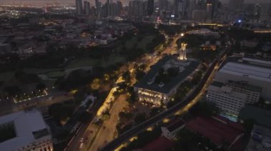 Aydınlanmış belediye binası ve çevre caddelerin yüksek açılı manzarası. Günümüz yüksek gökdelenleriyle gösterişli akşam manzarasını yukarı kaldırın. Manila, Filipinler.