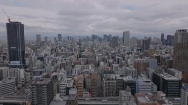 Bulutlu bir günde metropolün üzerinde ilerliyorlar. Metropolis 'in gökdelenli panoramik manzarası. Osaka, Japonya.