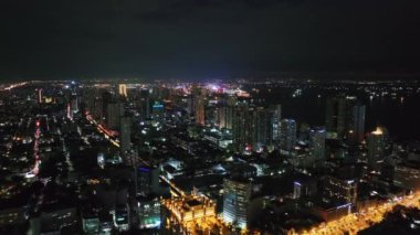 İleri, Gece Şehri 'nin üzerinde uçar. Modern yüksek binalarla Metropolis 'in havadan panoramik görüntüsü. Manila, Filipinler.