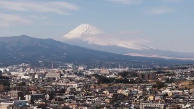 Fuji Tepesi 'nin altındaki binaların hava görüntüleri. Bulutların içindeki ikonik volkan dağı. Japonya.