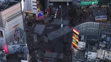 Şehre doğru giden arabaların yüksek açılı görüntüsü yaya geçidinden geçiyor. Shibuya Geçidi 'nde bekleyen bir sürü insan var. Tokyo, Japonya.