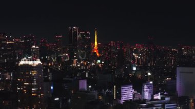 Geceleri modern metropolün havadan görünüşü. Tepesinde kırmızı ışıklar olan yüksek binalar. Aydınlatılmış Tokyo Kulesi. Tokyo, Japonya.