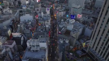 Şehirdeki caddelerin ve binaların yüksek açılı görüntüsü. Akşamları Shibuya Geçidi 'ndeki ticaret merkezi. Tokyo, Japonya.
