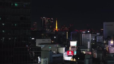 Şehir merkezindeki binaların havadan yükselen görüntüleri. Aydınlatılmış Tokyo Kulesi ile gece manzarası ortaya çıkıyor. Tokyo, Japonya.