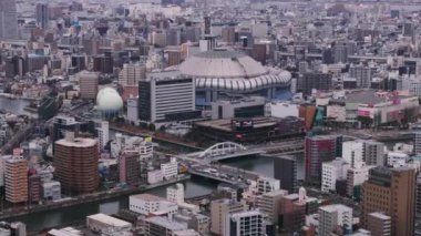 Osaka Kubbesi 'nin hava ve pan görüntüleri. Şehir merkezindeki binalarla çevrili modern tasarım beyzbol stadyumu. Osaka, Japonya, 20 Ocak 2024