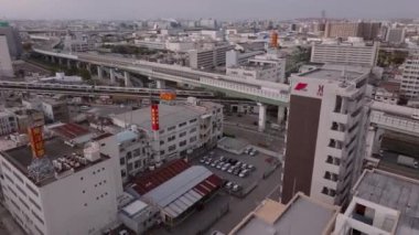 Metropolis 'te taşıma altyapısı. Yoğun şehir gelişimindeki yüksek caddenin altından geçen banliyö treninin hava görüntüleri. Osaka, Japonya, 20 Ocak 2024