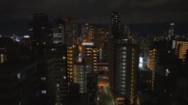 Metropolis 'teki yerleşim yerlerindeki çok katlı apartmanların hava yükselen görüntüleri. Geceleri yüksek katlı modern yapılar. Osaka, Japonya, 20 Ocak 2024