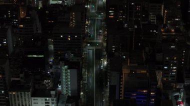 Gece şehrinin üzerinde uç. Şehirdeki caddelerden geçen araçların yüksek açılı görüntüsü. Osaka, Japonya, 20 Ocak 2024