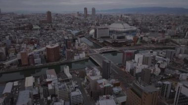 Şehir merkezinin üzerinde ilerliyorlar. Osaka Dome Beyzbol Stadyumu 'nun yanındaki nehrin üzerindeki geniş yol köprüsü. Sabah metropolünün hava görüntüsü. Osaka, Japonya, 20 Ocak 2024