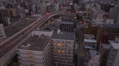 Şehir merkezindeki binaların ve yüksek şeritli yollarda giden arabaların yüksek açılı görüntüsü. Yukari egilmek sabah sehrini ortaya çikarir. Osaka, Japonya, 20 Ocak 2024