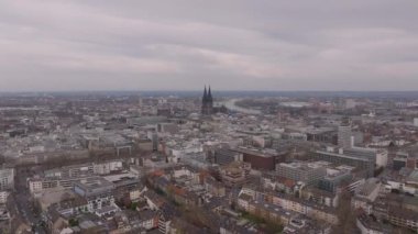 Almanya 'nın Köln şehrinin dinamik manzarası bulutlu bir gökyüzüne karşı ünlü katedrali ve modern mimariyi sergiliyor..