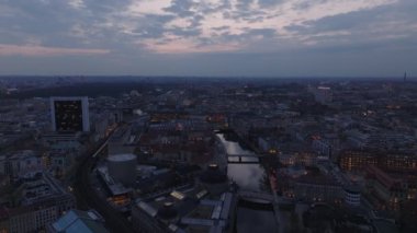 Alacakaranlıkta Berlin 'deki Friedrichstrasse' nin hava görüntüsü, canlı ışıklar, nehir ve ikonik gökyüzü karşısında gökyüzü.