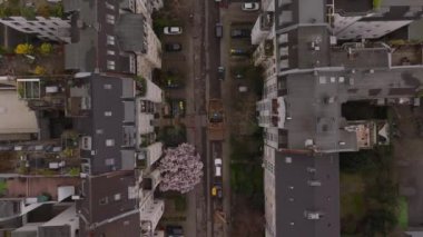 Kuzey Avrupa 'da park halindeki arabaların, çiçek açan ağaçların ve şehir binalarının yer aldığı yerleşim yerinin kuş bakışı görüntüsü.