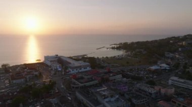 İnsansız hava aracı, Jamaika kıyı kasabasında huzurlu bir gün doğumu yakalıyor. Renkli şehir manzarasını ve sakin denizi vurguluyor..