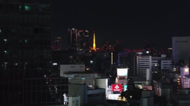 Şehir merkezindeki binaların havadan yükselen görüntüleri. Aydınlatılmış Tokyo Kulesi ile gece manzarası ortaya çıkıyor. Tokyo, Japonya, 10 Şubat 2024