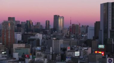 Modern yüksek katlı ofis ya da Metropolis 'teki konut binaları. Gökdelenler ve Tokyo Kulesi alacakaranlıkta açık renkli gökyüzüne karşı. Tokyo, Japonya, 10 Şubat 2024