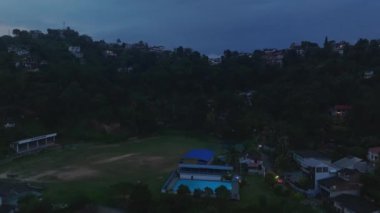 Kandy 'nin alçak irtifa görüntüsü, alacakaranlıkta Sri Lanka, yemyeşil ve tepe evleriyle sakin manzarayı gösteriyor, bu şehrin güzelliğini gözler önüne seriyor..