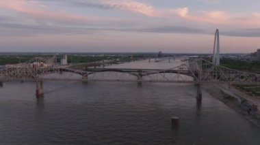 St. Louis 'deki Mississippi Nehri üzerindeki köprülerin hava manzarası, yumuşak akşam güneşi ışığı ve arka planda bir şehir silüeti. Kentsel, ulaşım ve seyahat kavramı.