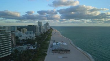 Gün batımında Miami Plajı 'nın havadan görüntüsü. Yükselen binalar, sahil tesisleri ve canlı bir gökyüzünün altındaki sakin Atlantik okyanusu..