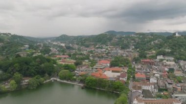 Yukarıdan canlı Kandy kasabası yemyeşil, tarihi mimarisi ve bulutlu bir gökyüzü altında sakin göl manzarasını sergiliyor. Seyahat ve turizm kavramı.