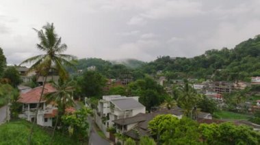 Kandy, Sri Lanka tepelerindeki yemyeşil bir yerleşim bölgesinin havadan görüntüsü. Manzaralı tropik yeşillik ve kameralar manzarayı çekerken görünen evler..